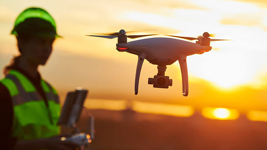 Photo of a female technician using a drone at sunrise