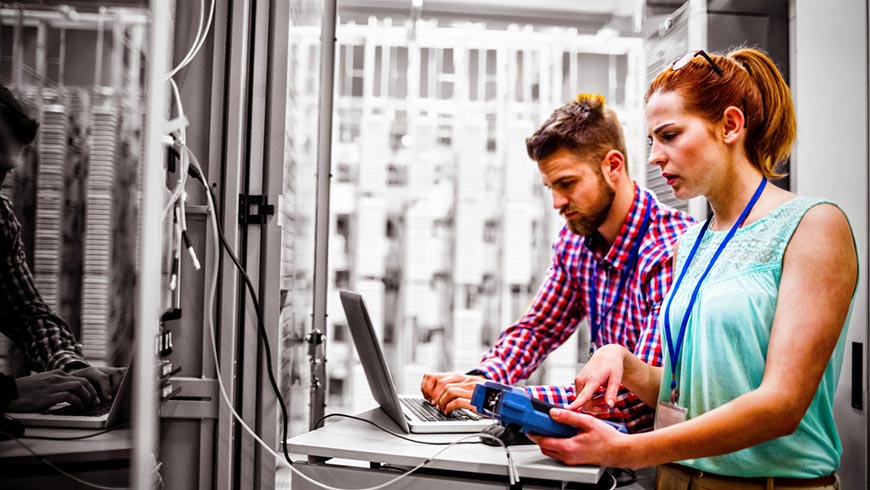 Photo of a man and woman in a data center using equipment