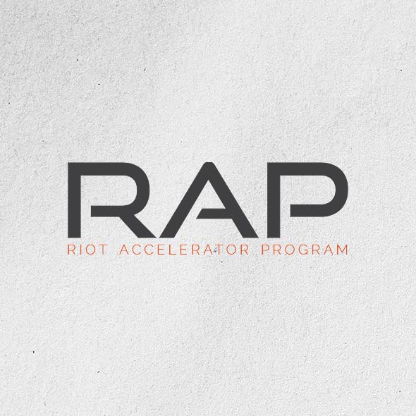 RIoT Accelerator Program Logo - Black and orange sans-serif type over gray textured background